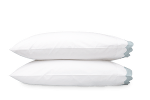Two white pillows from the Matouk Lorelei Bedding Collection in Pool, featuring a light gray edging and crafted from soft 600 thread count Milano percale for a luxurious touch.