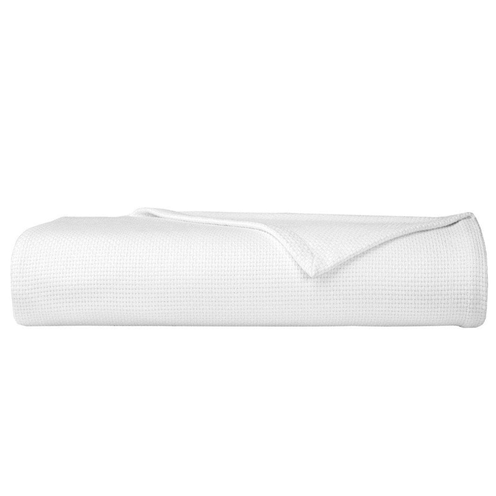 The Yves Delorme Maillon Blanc Coverlet, a white waffle-textured cotton blanket made in Turkey, is displayed neatly folded against a plain white background.
