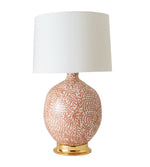 The Marfa Round Dappled Coral Lamp by Paul Schneider Ceramics features a ceramic gold base, solid brass dimmer socket, and a plain white cylindrical shade.
