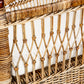 A close up of a hand-woven PALECEK rattan chair with a seat cushion.