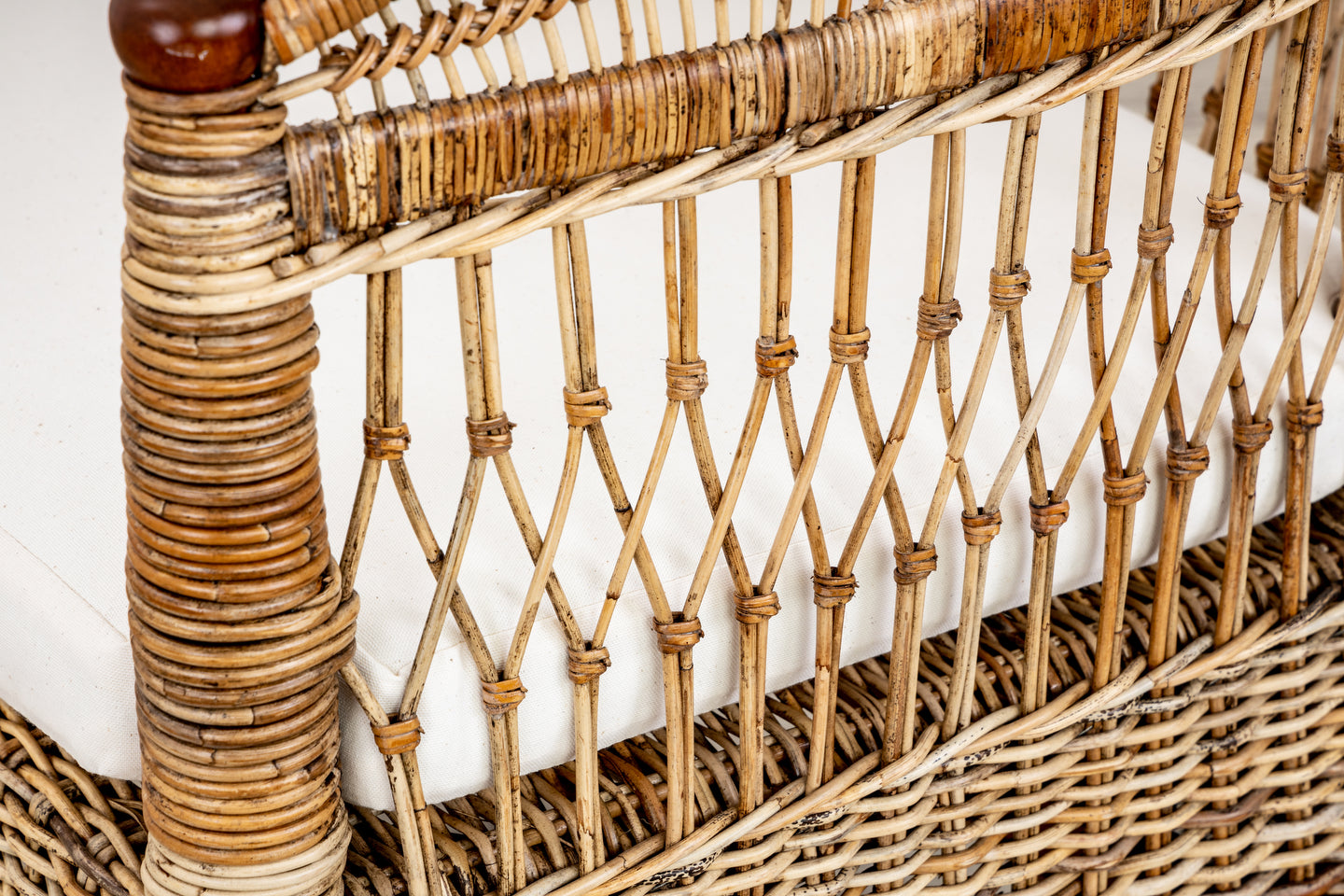 A close up of a hand-woven PALECEK rattan chair with a seat cushion.