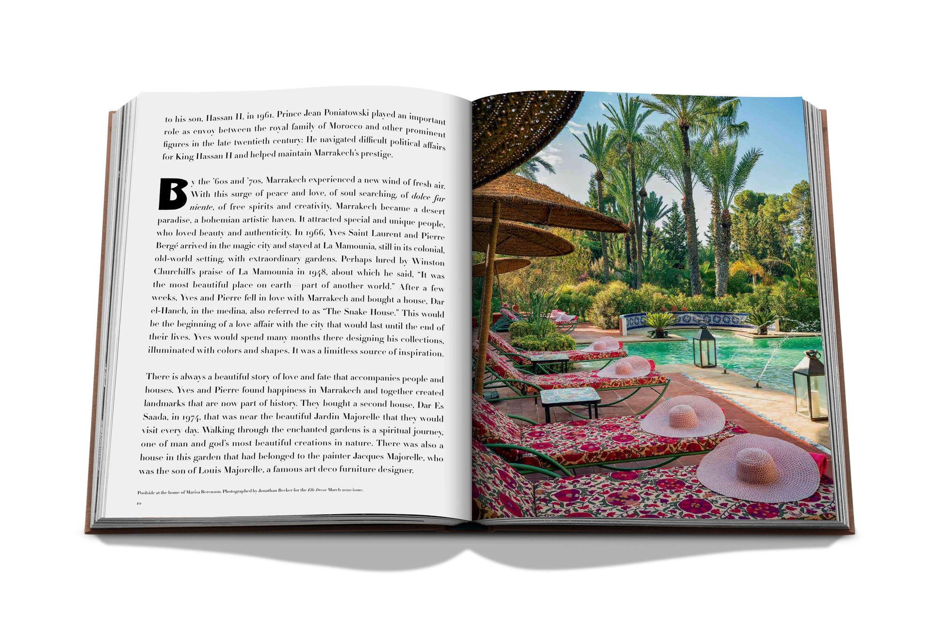 An open book displaying a printed image of a tropical resort inspired by Assouline's interpretation of Moroccan arts, with palm trees and a poolside area reminiscent of Marrakech culture.