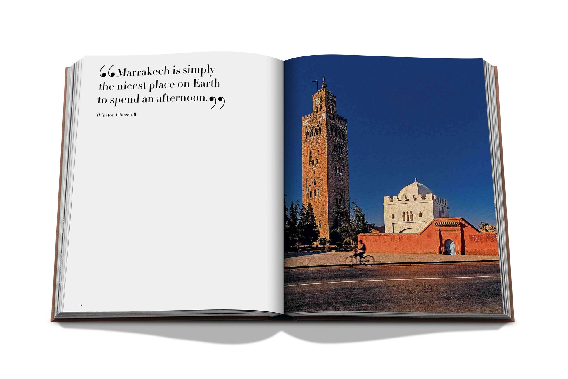 An open Marrakech Flair book by Assouline with a photograph of a historical building in Marrakech and a quote praising the city's vibrant Moroccan arts.