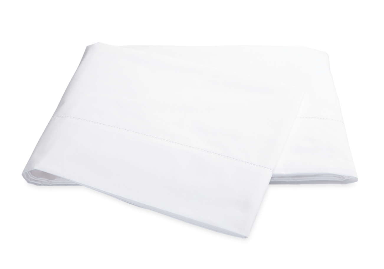 A pair of neatly folded white Matouk Milano Bedding Collection pillowcases isolated on a black background.