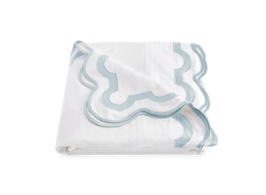 A neatly folded white sheet with a light blue and gray border from the Matouk Mirasol Bedding Collection, Pool, crafted in 600 thread count Egyptian cotton percale.