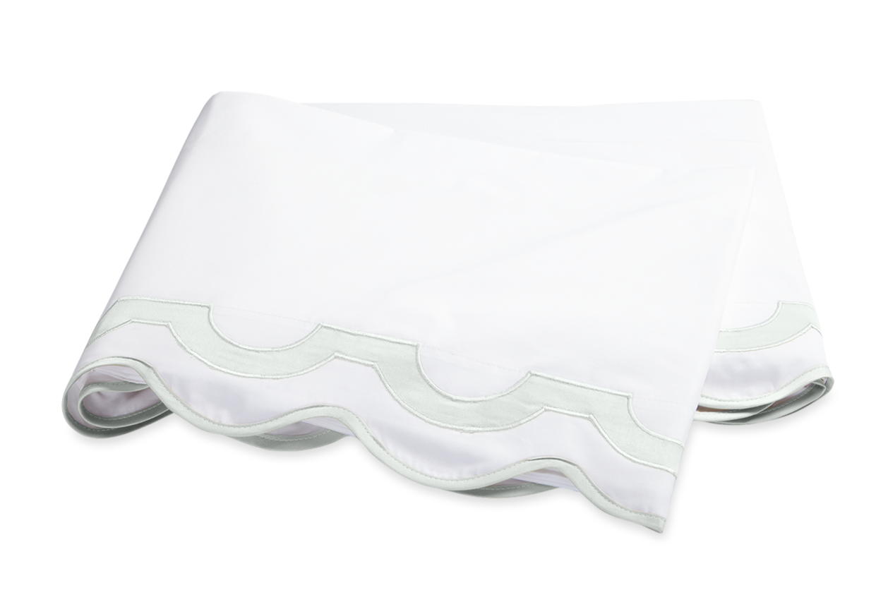 The Mirasol Bedding Collection, Opal by Matouk features a folded white sheet with a scalloped edge and light green border, crafted from 600 thread count Egyptian cotton percale, shown on a plain background.