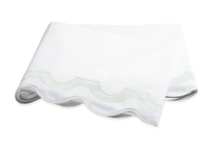 The Mirasol Bedding Collection, Opal by Matouk features a folded white sheet with a scalloped edge and light green border, crafted from 600 thread count Egyptian cotton percale, shown on a plain background.