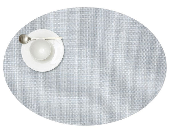 A Chilewich Oval Placemat, Sky, with a spoon and fork on it.