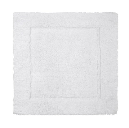 The Yves Delorme Prestige Blanc Bath Mat is a white rectangular mat with a subtle raised border, crafted from 100% cotton for plush comfort, shown from above on a plain background.
