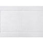 The Yves Delorme Prestige Blanc Bath Mat is rectangular, white, and features a simple textured border. Made from 100% cotton, it offers a soft, plush, and luxurious feel.