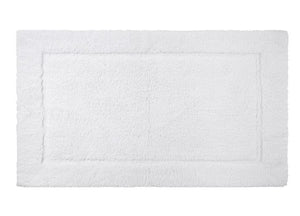 The Yves Delorme Prestige Bath Mat in Blanc is a white rectangular mat crafted from 100% cotton with a textured border design, plush cut pile for softness, and non-slip backing for safety.