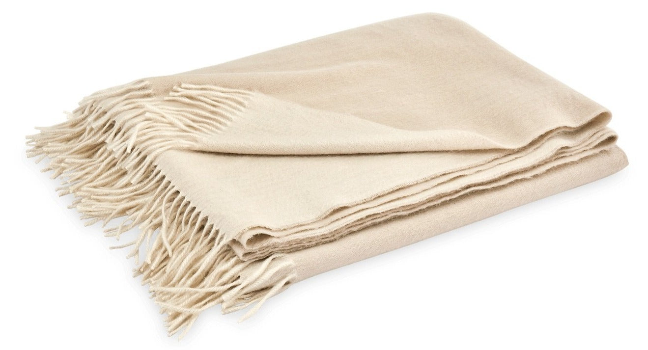 Displayed against a white background, the Matouk Paley Cashmere Throw by Matouk is an oversized beige throw adorned with fringe edges.