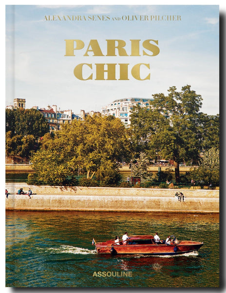 Cover of the 'Paris Chic' book by Assouline featuring a boat on the Seine River with sophisticated homes in Paris and Parisian architecture in the background.