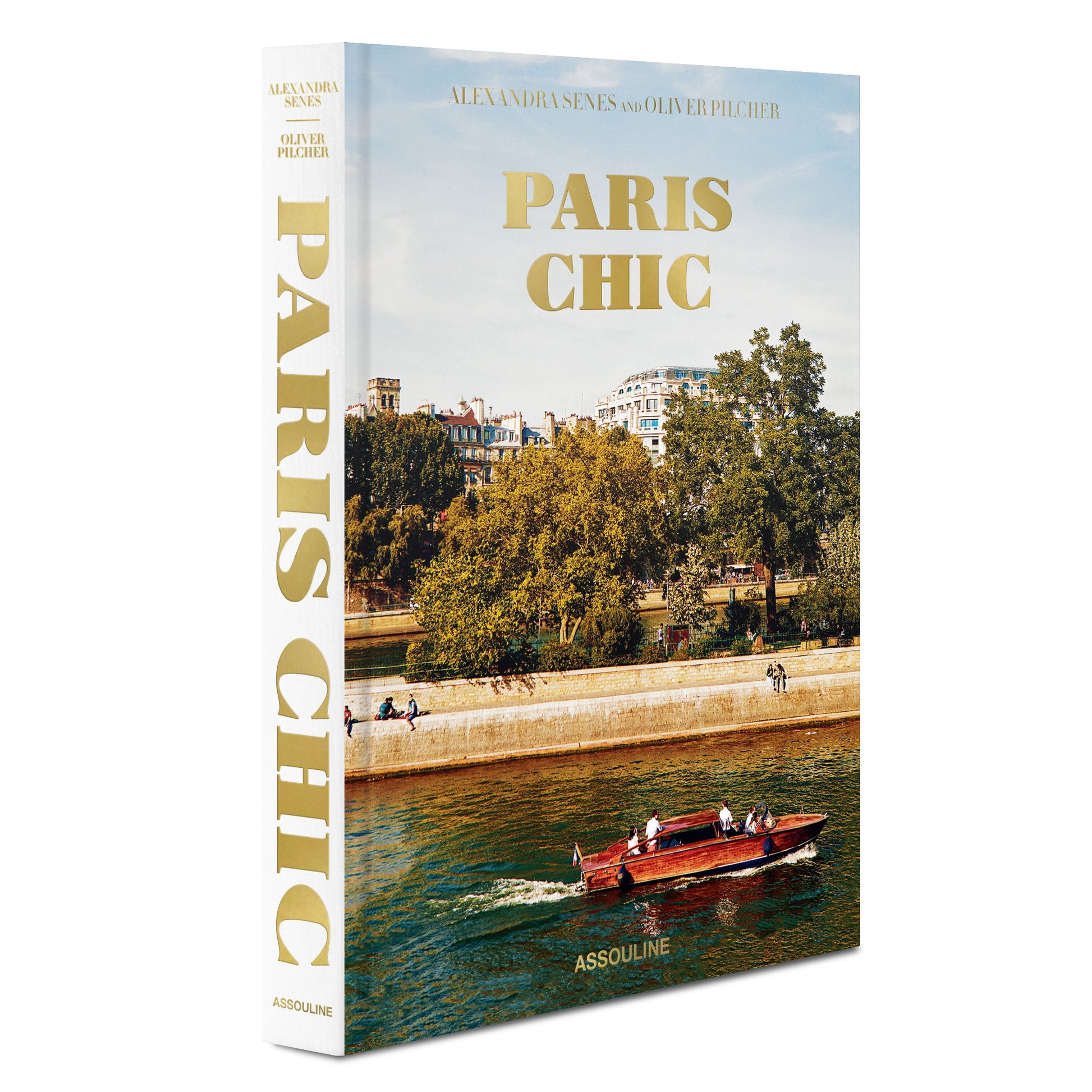 A book titled "Paris Chic" by Alexandra Senes and Oliver Pilcher, published by Assouline, featuring a cover image of a boat on the Seine River with sophisticated homes in Paris.