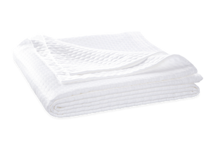 The Matouk White Pearl Bedding Collection features a neatly folded, quilted matelassé blanket made from luxurious Egyptian cotton, sitting against a plain background.