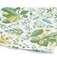 A folded fabric featuring a floral pattern with green leaves and yellow flowers on a white Matouk Pomegranate Bedding Collection, Citrus background.