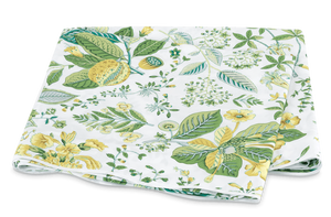 A folded fabric featuring a floral pattern with green leaves and yellow flowers on a white Matouk Pomegranate Bedding Collection, Citrus background.