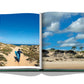 A photo book of a man walking on sand with a surfboard in Punta del Este, capturing the beach resort atmosphere by Assouline.