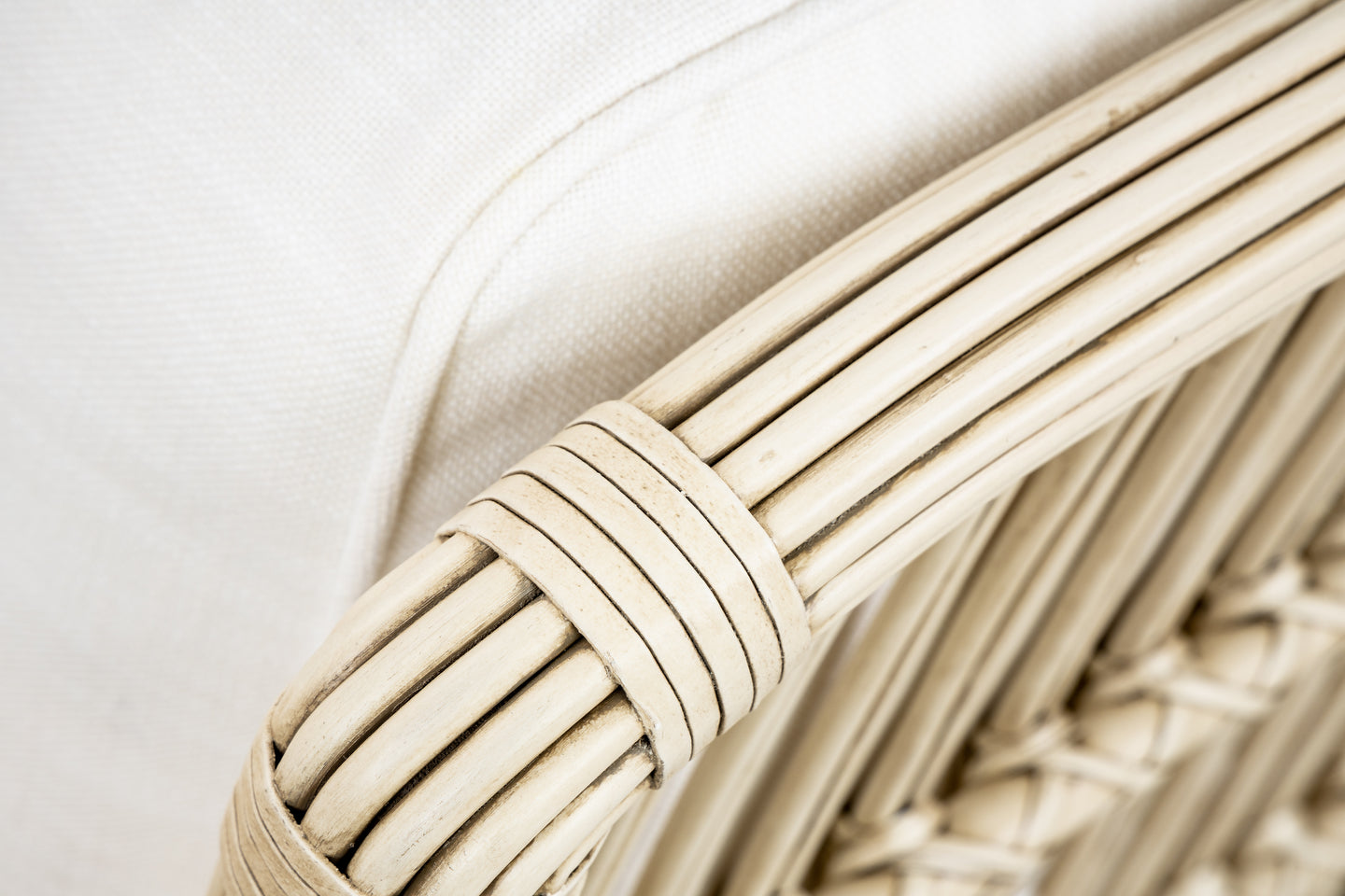 Close-up of a PALECEK President's State Chair armrest, featuring a white cushion and visible woven rattan accents that showcase the natural texture and color.