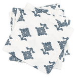 A stack of Matouk's Rubia Navy Napkin Set, featuring white OEKO-TEX® Standard 100 certified napkins with a blue floral pattern, is arranged slightly askew on a black background.