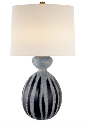 The Gannet Table Lamp, Drizzled Cobalt by Visual Comfort has a round, textured ceramic base with vertical blue and gray stripes and a large white cylindrical shade. It supports up to 150W with an E26 dimmer.