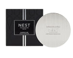 The Nest Silver Classic Candle Lid is shown next to its black box with a vertical silver stripe, highlighting its design for fragrance preservation.