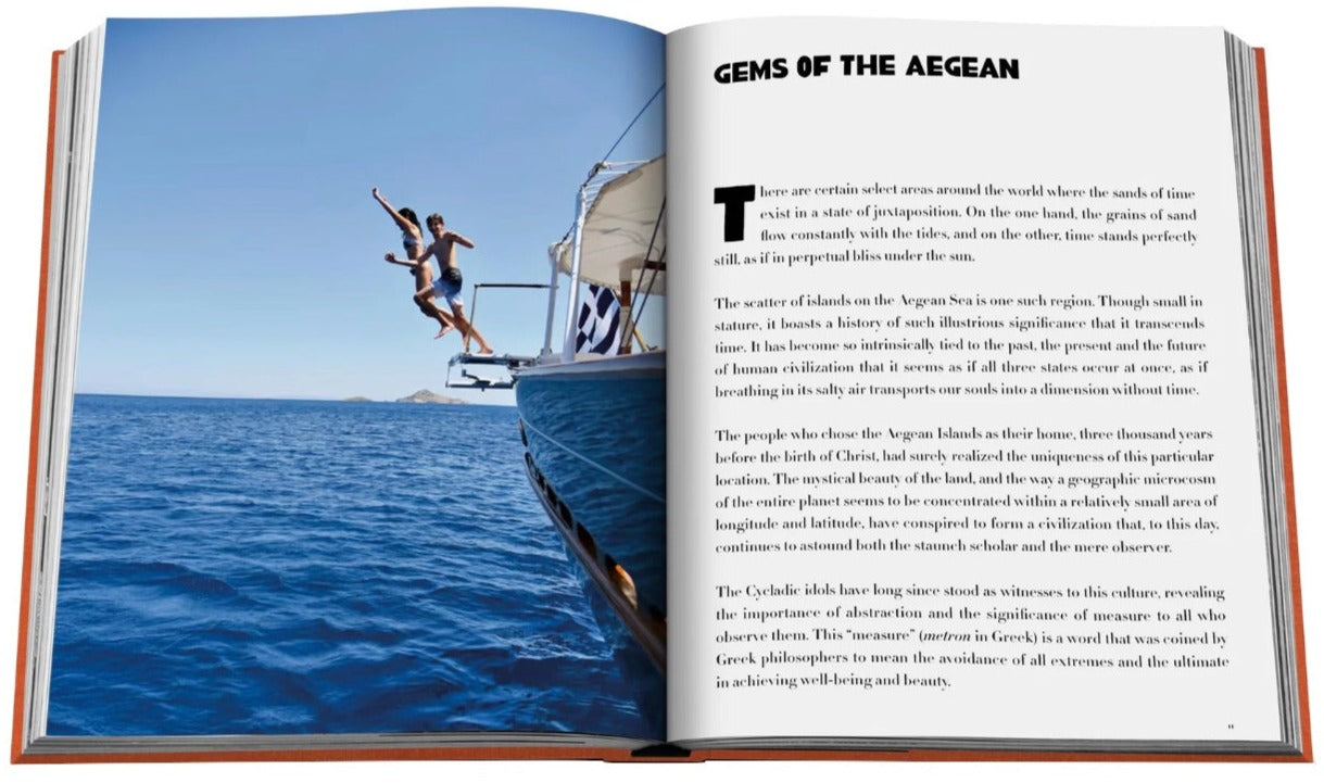 Open Greek Islands book featuring an article on "gems of the Aegean Sea" with a photograph of a person climbing the mast of a sailing boat on the left page by Assouline.