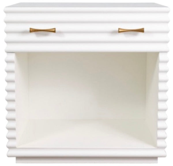 The Brighton Bedside Table by Mr Brown boasts a stunning white lacquered ribbed design, complemented by aged brass hardware and two refined gold-colored handles. Its open central shelf adds a touch of sophistication to any space.