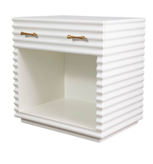 Introducing the Brighton Bedside Table by Mr Brown: This elegant piece features a ridged texture in a sleek white lacquer finish. It comes with one top drawer accented by aged brass hardware and an open shelf below, making it perfect for any compact living space.