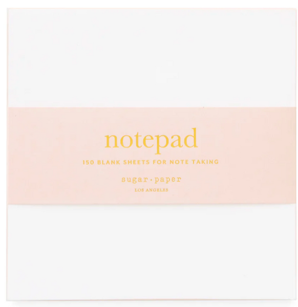 The Sugar Paper Painted Pad in Pink, featuring a white notepad with a pink band and labeled with "notepad" and "150 blank sheets for note taking," is an everyday essential from Sugar Paper, Los Angeles. It's perfect for on-the-go notes and makes jotting down ideas effortless wherever you are.