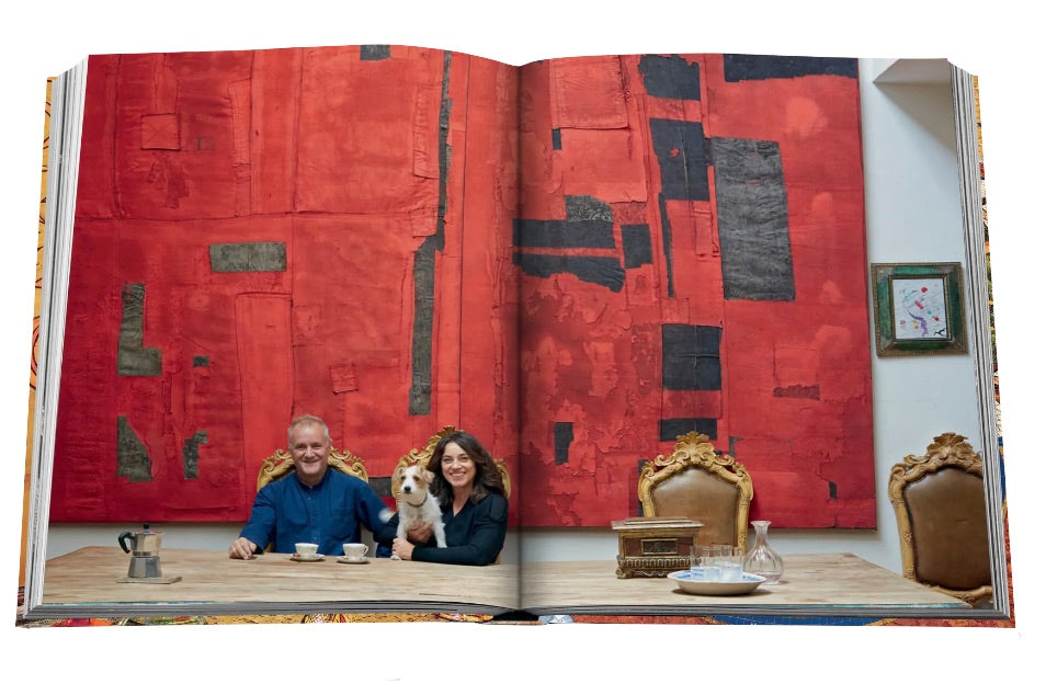 Two individuals and a dog seated at a table with oversized Milan Chic art books in front of a large red artwork displayed at Fondazione Prada by Assouline.