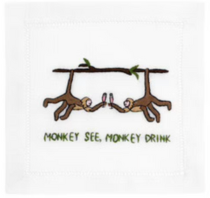 August Morgan’s Monkey See Monkey Drink Cocktail Napkins feature two monkeys clinking cocktail glasses while hanging from a branch, with "MONKEY SEE, MONKEY DRINK" elegantly displayed beneath them.