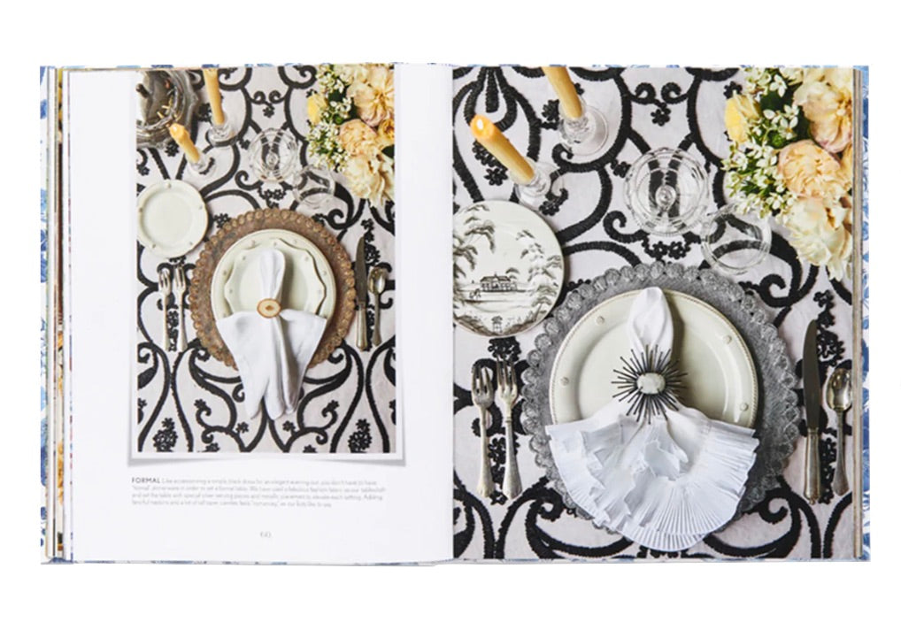 Discover the beauty of dining with \"Juliska Together at the Table: Entertaining At Home With the Creators of Juliska,\" showcasing refined table settings featuring intricate Juliska tableware and decorative napkins. Set on a patterned tablecloth adorned with flowers and candles, this book celebrates life’s moments with dining elegance.