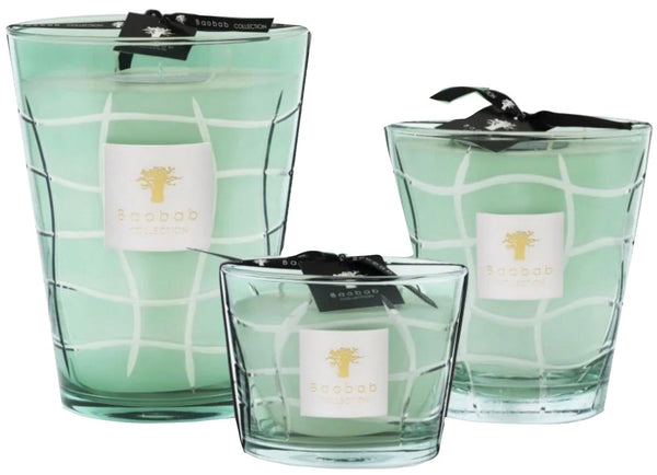 Three Baobab Collection Waves Nazare candles in varying sizes, in green glass containers with a tortoise shell pattern, tied with peppermint-colored ribbons.