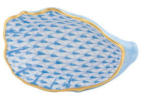 The Herend Oyster Shell is a blue and white porcelain dish shaped like a shell, hand-painted with a scalloped blue scale pattern, gold rim, and refined artistic detail.