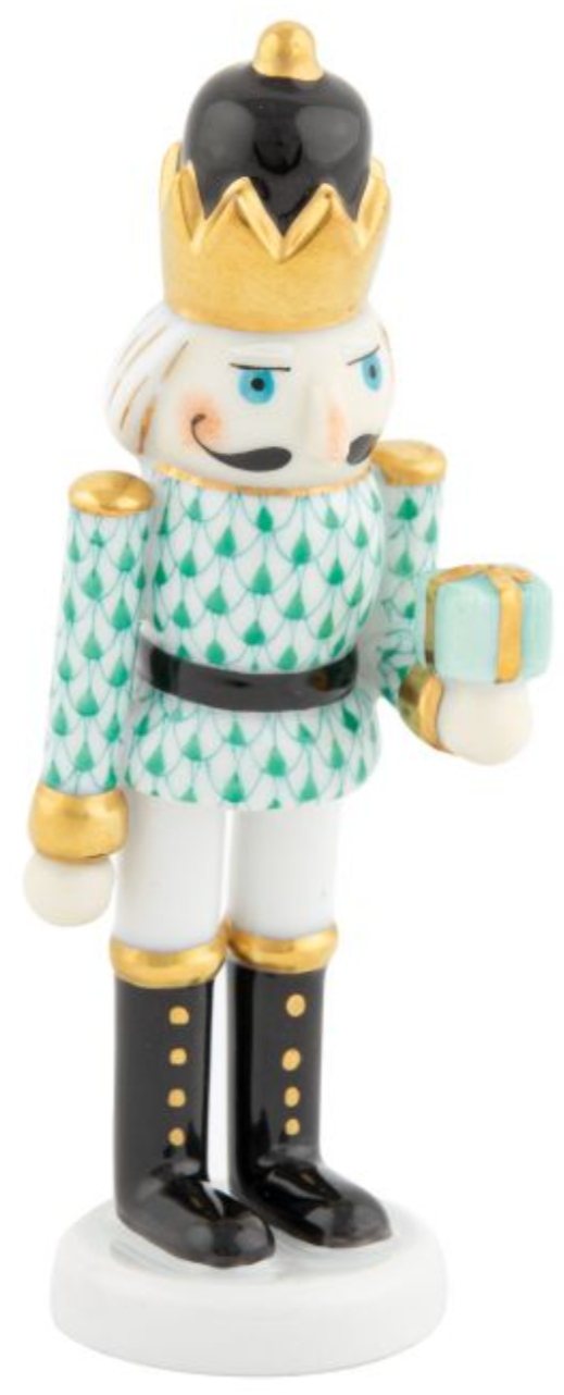 The Herend Nutcracker with Gift is a porcelain figurine of a crowned nutcracker soldier in green, gold, black, and white with hand-painted details, holding a gift box—ideal for artistic appreciation.