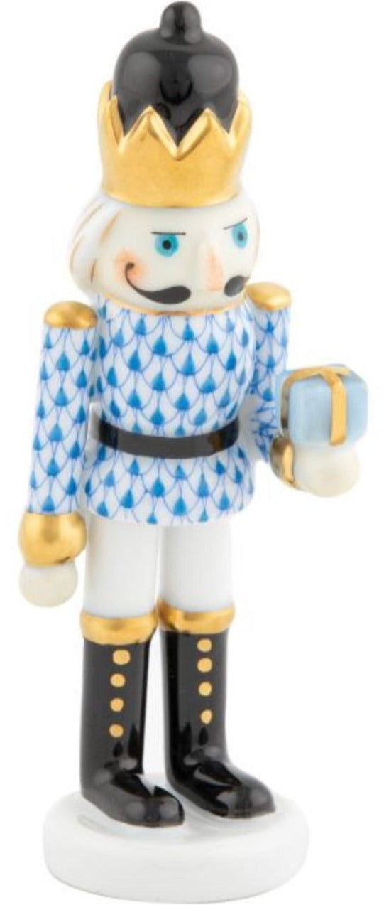 The Herend Nutcracker with Gift features a gold crown, blue patterned jacket, black boots, and a small blue gift box—all exquisitely hand painted for true artistic appreciation.