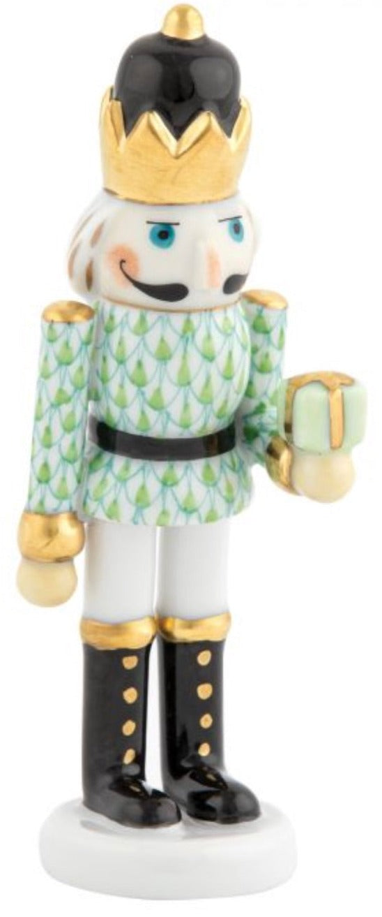 The Herend Nutcracker with Gift features a gold crown, green patterned jacket, black boots, and a small wrapped present, highlighting artistic hand-painted design.