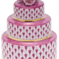 The Herend Wedding Cake is a three-tiered round porcelain box, hand-painted in pink with gold leaf accents and topped with a delicate pink flower ornament.