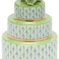 The Herend Wedding Cake is a three-tiered decorative box with green and gold accents, white patterned sides featuring hand-painted designs, and a green ceramic flower on top.