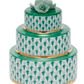 Herend "Wedding Cake" is a three-tiered porcelain box featuring hand-painted green and white patterns, gold edges, and a green flower topper, inspired by the Queen Victoria collection.