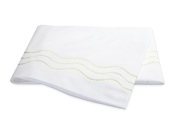 Folded white Matouk Serena Bedding Collection, Spring Green towel with green decorative stitching on a black background, made of long-stapel cotton Sierra percale sheeting.