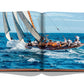 Open book with a photograph of a sailboat navigating through rough ocean waves, crew members managing the sails, capturing the thrill of St Tropez Soleil by Assouline.