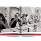 Open book displaying a black-and-white photo of five people enjoying a meal and laughing at an outdoor table, reminiscent of the carefree moments you'd find at places like **St Tropez Soleil by Assouline**.