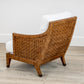 A St. Germaine Chair by McGuire Furniture, featuring a white cushion and elegant cane wrap design, rests on a light wood floor against a pristine wall.