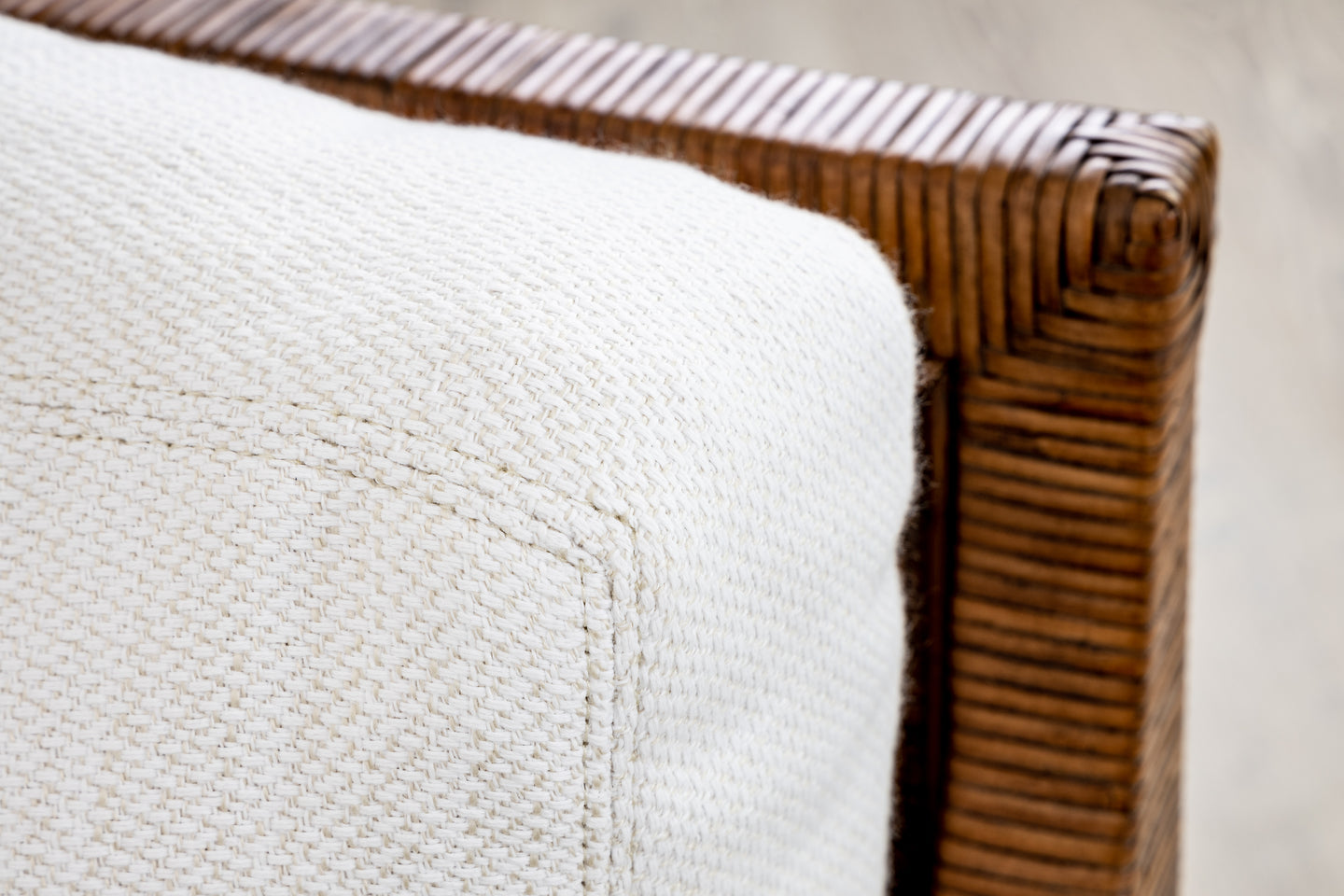 A beige woven cushion sits gracefully on the brown wicker frame of McGuire Furniture's St. Germaine Chair, highlighting its elegant cane wrap detailing.