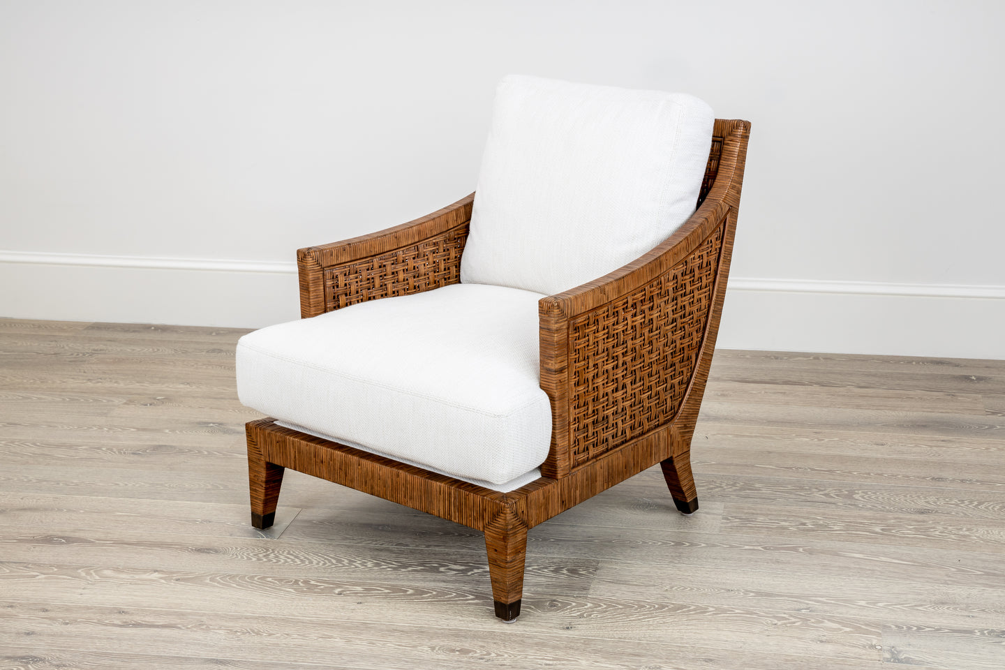 A McGuire Furniture St. Germaine Chair with a cane wrap and Perennials Sea Salt Cognac Fabric cushions sits elegantly on a light wood floor against a pristine white wall.