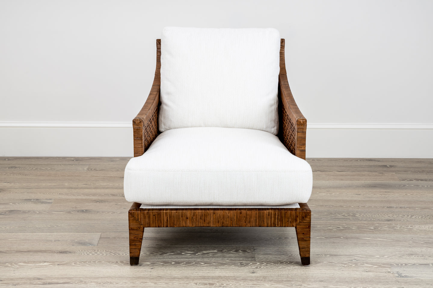 The McGuire Furniture St. Germaine Chair, featuring cushions in Perennials Sea Salt Cognac Fabric, is elegantly placed on a light wood floor against a plain white wall.