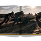 A team of individuals pushing a vintage race car on a sandy surface, captured in a photograph within an open book at The Race of Gentlemen by Assouline.