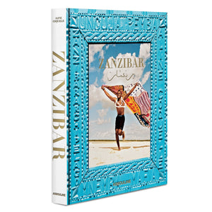 A book titled "Zanzibar" by Assouline with a photograph of a person running on a beach by the Indian Ocean while holding a flag on the cover. The book features a blue decorative border.